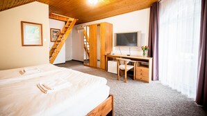 Un dormitorio con cama, escritorio, silla, televisor y una escalera.
