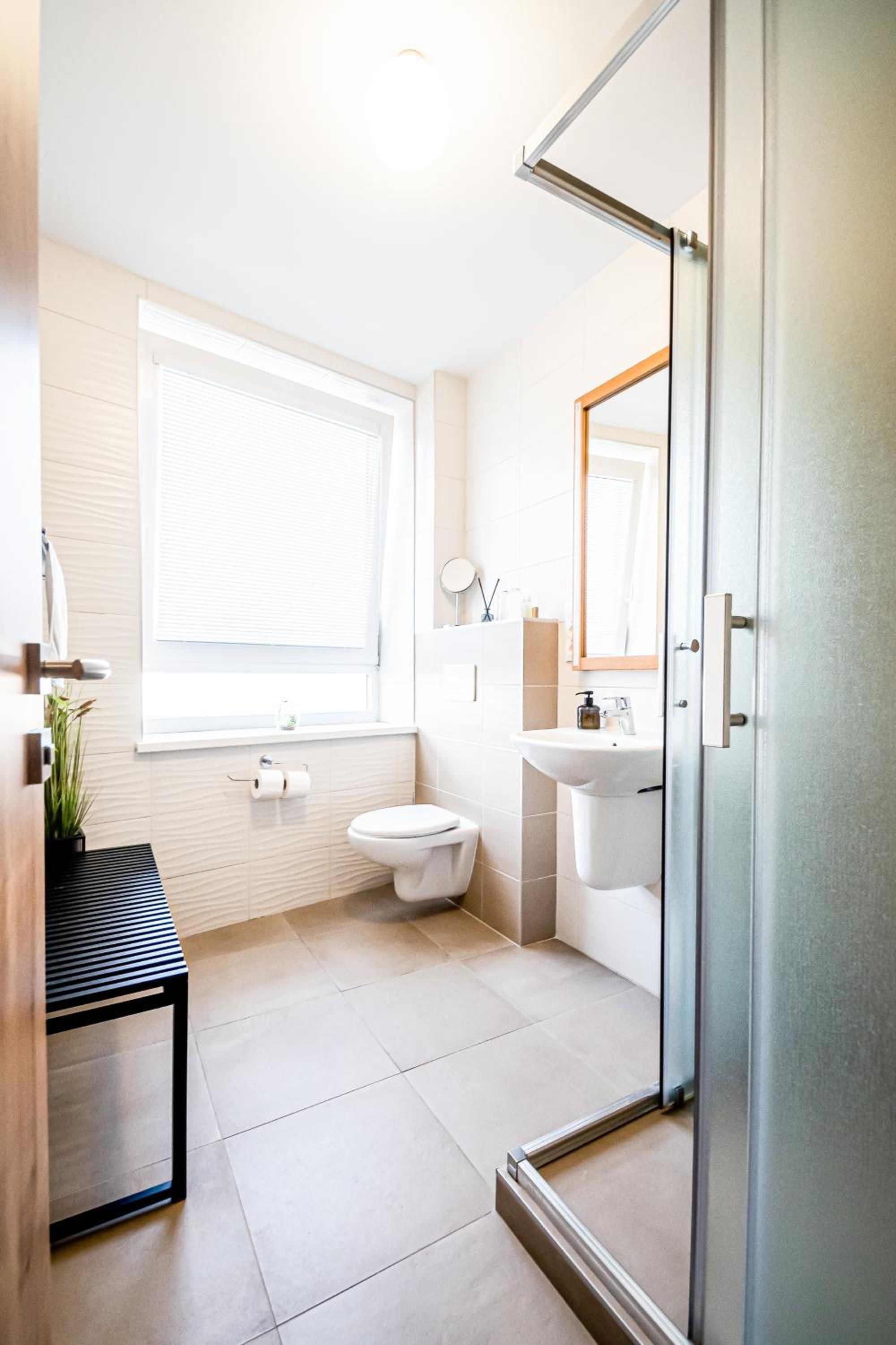 Un baño moderno con inodoro, lavabo y zona de ducha.