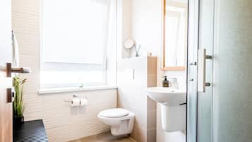 Un baño moderno con inodoro, lavabo y zona de ducha.