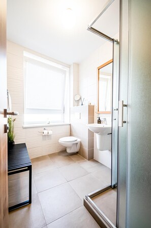 Un baño moderno con inodoro, lavabo y zona de ducha.