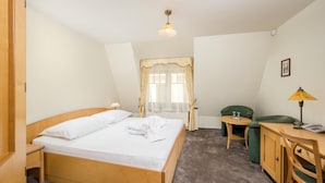 Una habitación de hotel con una cama doble, un escritorio con lámpara, una silla y una mesita.
