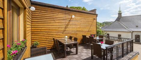 Un patio al aire libre con paredes de madera, mobiliario de mimbre y piso de ladrillo.