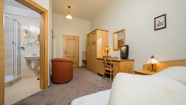 Una habitación de hotel con cama, escritorio, silla y un taburete pequeño.