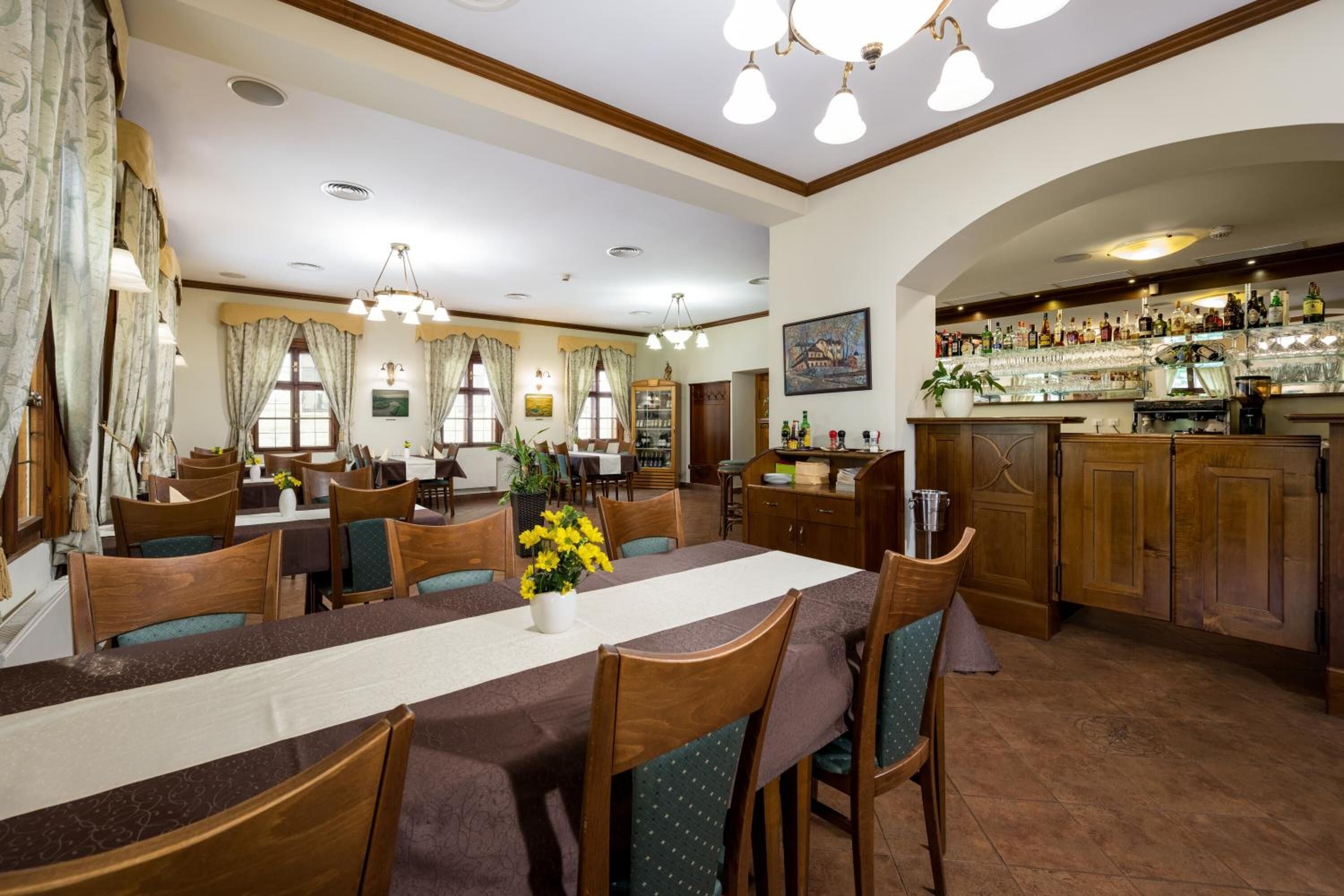 A dining area with a long table, chairs, and a bar area with shelves of bottles.
