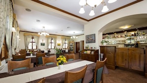 Un comedor con una mesa larga, sillas y una zona de bar con estantes llenos de botellas.