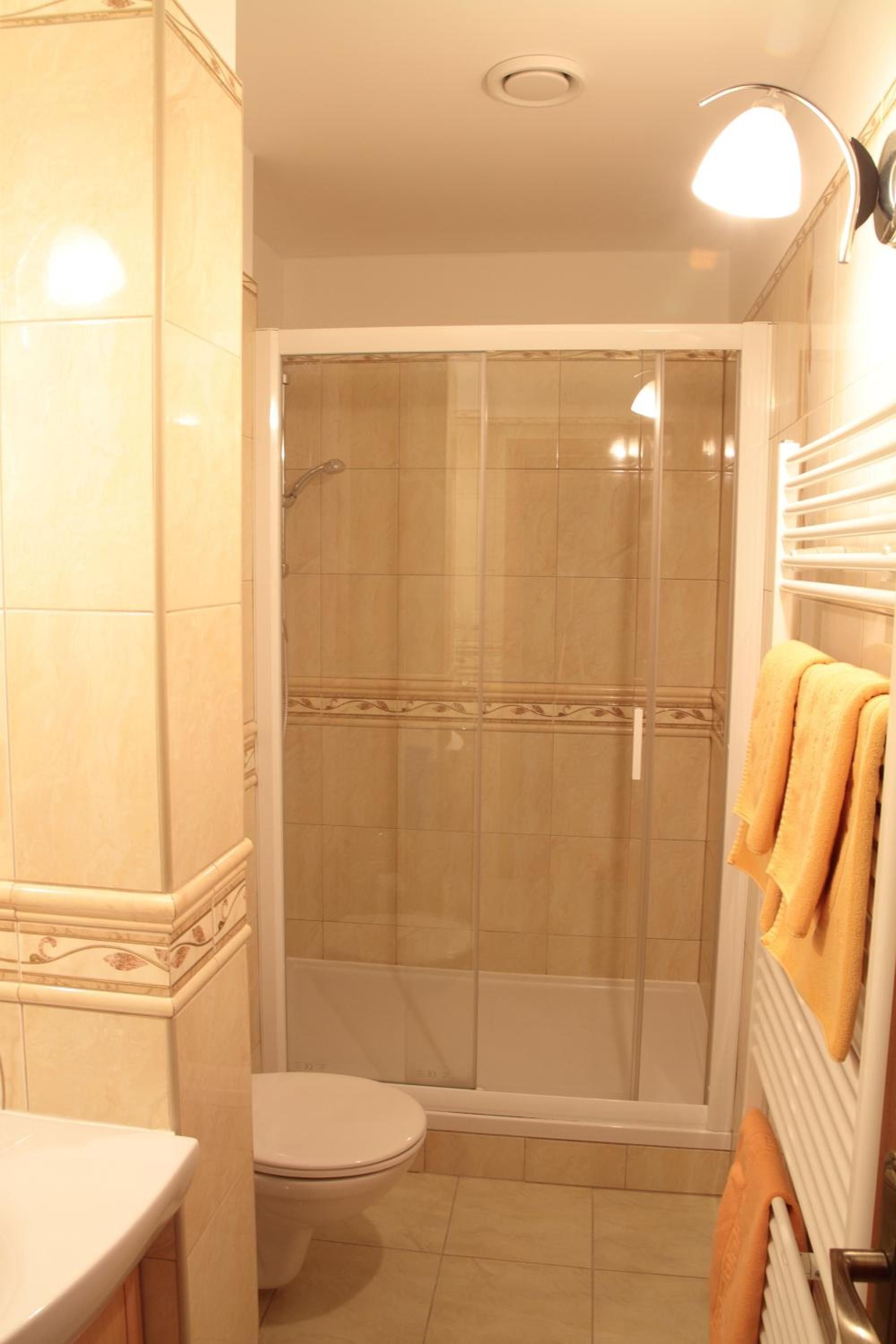 A bathroom with a toilet, a shower enclosure, and a towel rack with towels.