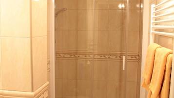 A bathroom with a toilet, a shower enclosure, and a towel rack with towels.