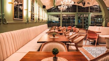 Ein Restaurant mit einer langen Sitzbank, Holztischen und -stühlen.