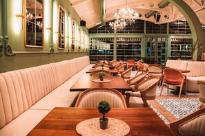 Ein Restaurant mit einer langen Sitzbank, Holztischen und -stühlen.