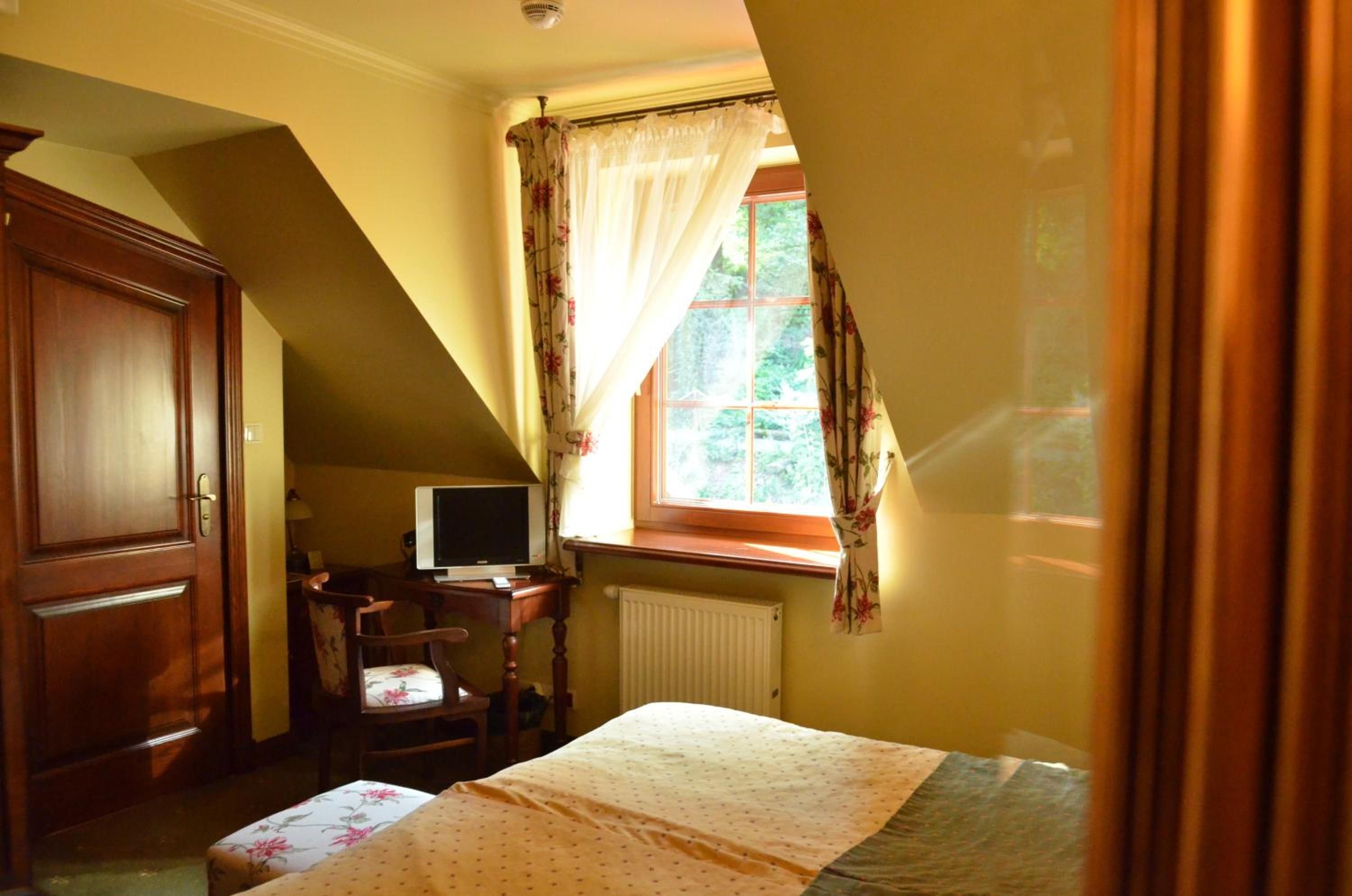 A bedroom with a bed, a desk with a computer, a chair, and a wardrobe.