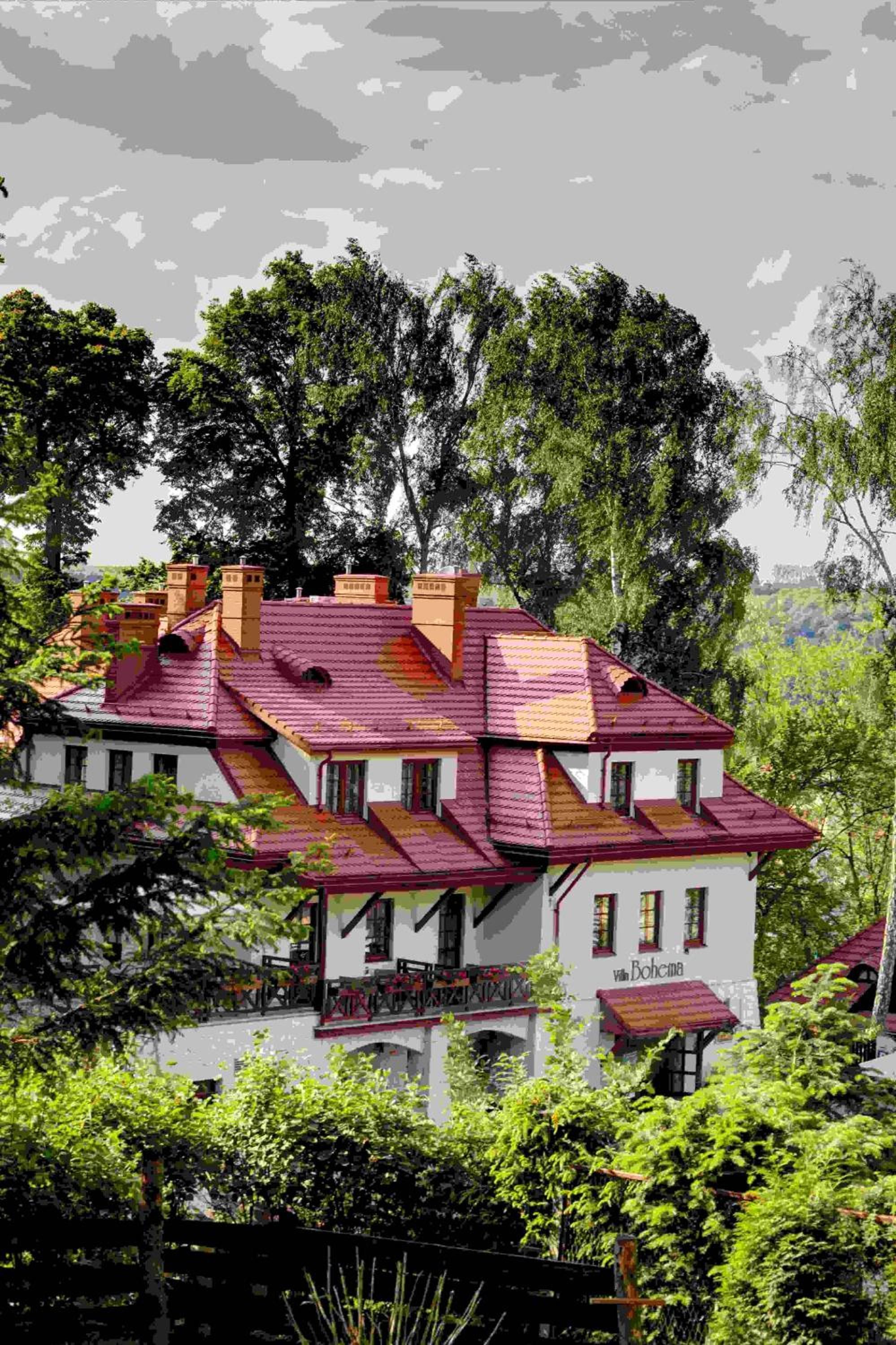A multi-story building with a red-tiled roof, white walls, and multiple chimneys.