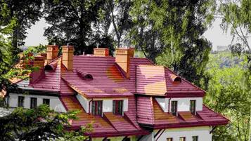 A multi-story building with a red-tiled roof, white walls, and multiple chimneys.