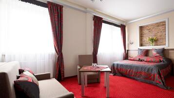 A hotel room with a bed, a sofa, a table, and a chair.