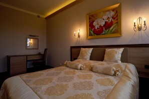 A hotel room with a large bed, two bedside tables, a desk, and a painting on the wall. - Hotel Polita Nski (Rybnik)