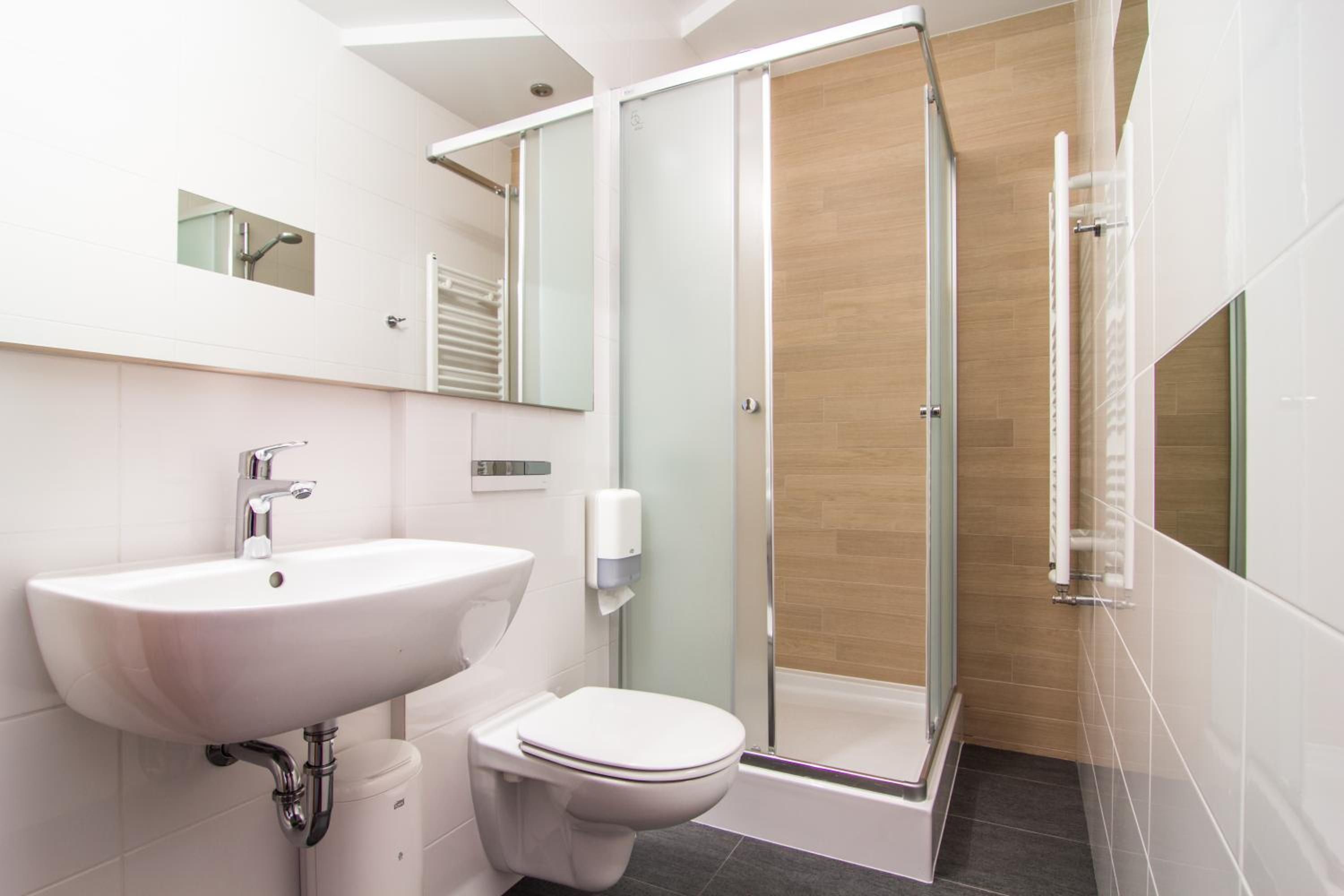 A modern bathroom with a white sink, toilet, and glass shower enclosure.