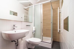 A modern bathroom with a white sink, toilet, and glass shower enclosure.