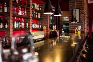 Een bar met flessenkast, een toog en twee hanglampen.