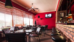 Un restaurante con pared roja, mesas de madera y sillas negras.