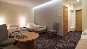 Habitación de hotel con dos camas, una silla, una mesita y una puerta.