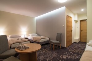 A hotel room with two beds, a chair, a small table, and a door. - Zajazd Magnolia Airport Modlin (Pomiechowek)