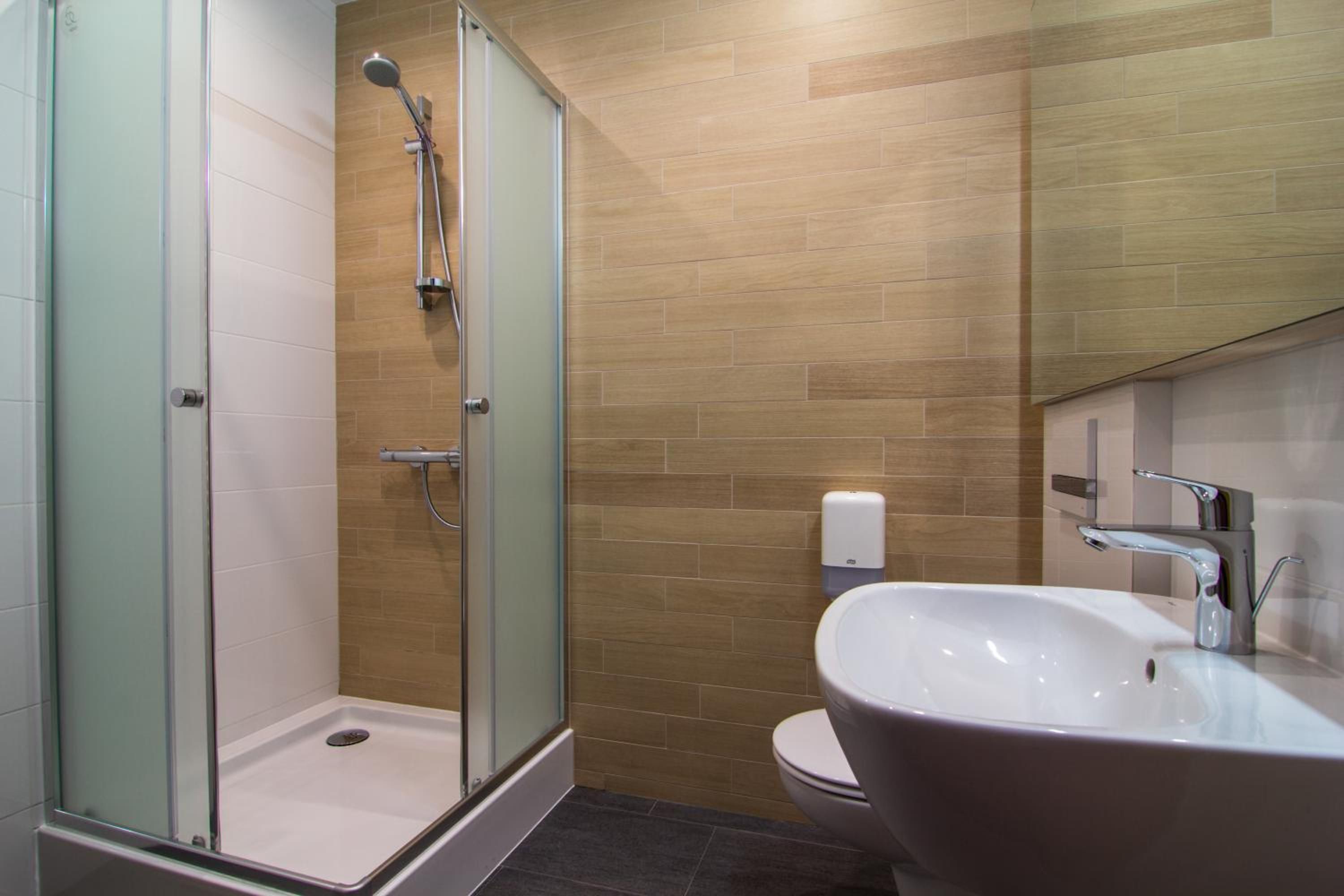 A modern bathroom with a glass-enclosed shower, a white sink, and a toilet.