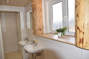 A bathroom with two sinks, a window, and a wooden accent wall. - Naturfreundehaus Veilbronn (Heiligenstadt in Oberfranken)
