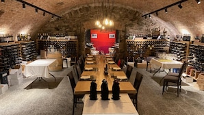 A wine cellar with a long table set for dining, surrounded by wine racks. - Hotel Ristorante Grotto Serta (Lamone)