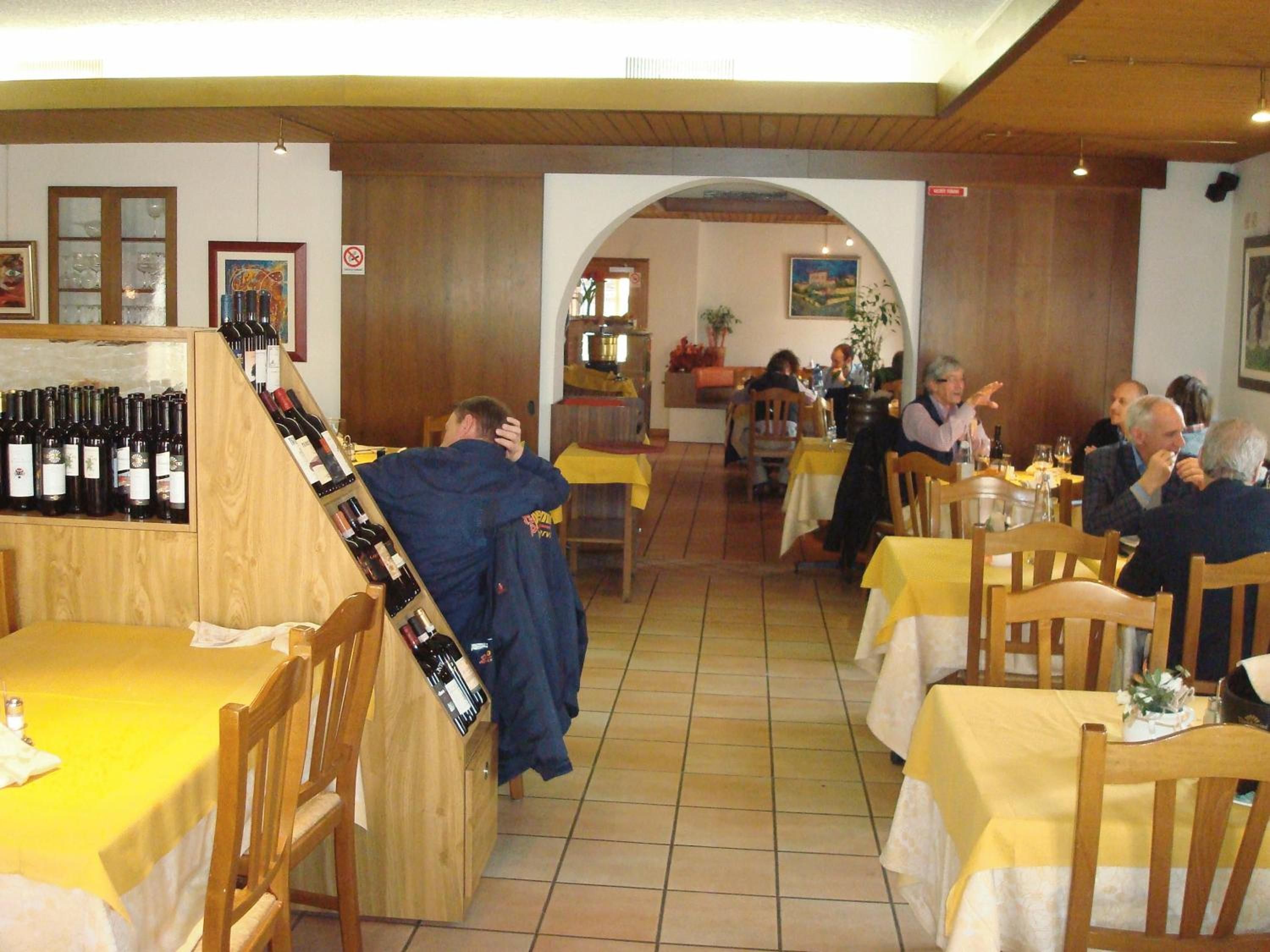 A restaurant interior with wooden tables, chairs, and a wine rack.