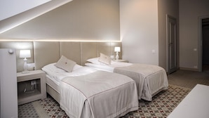 A hotel room with two beds, a small desk, and a patterned floor.