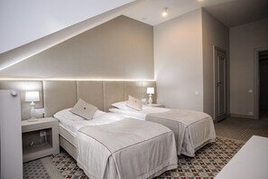 Habitación de hotel con dos camas, un escritorio pequeño y piso con estampado.