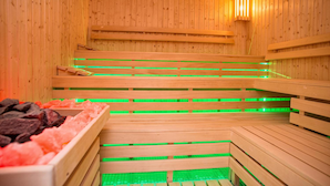 A sauna with wooden benches and green lighting.