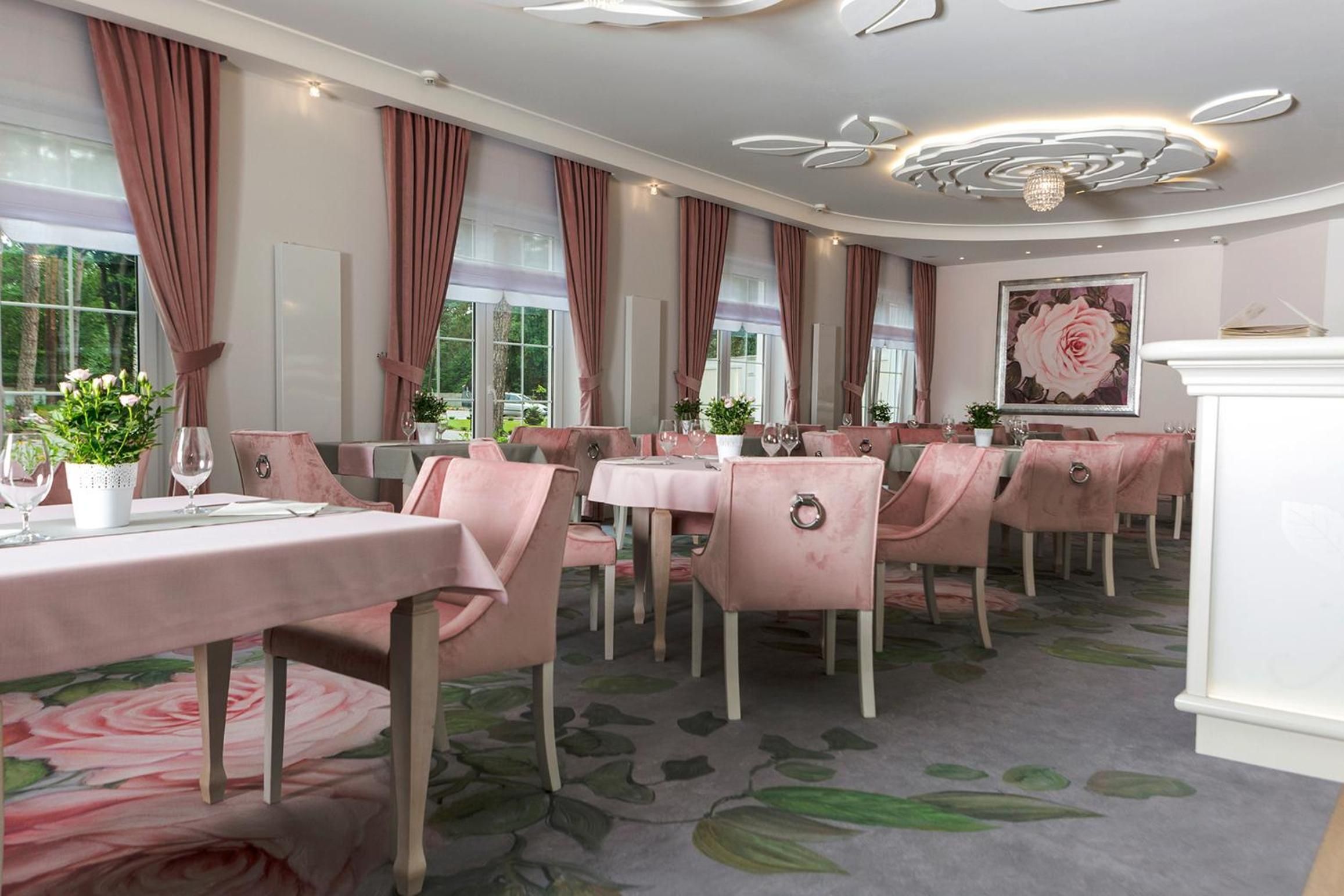 A restaurant with pink chairs, round tables, and a floral carpet.