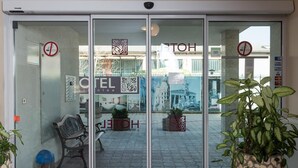 Ein Hotel Eingang mit Glastür, einer Bank und Blumentöpfen.