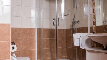 A modern bathroom with a glass-enclosed shower, a toilet, and a sink with a mirror.