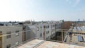 Eine Dachterrasse mit Blick auf umliegende Gebäude und einen klaren Himmel.