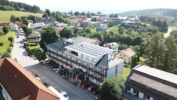 Ein mehrstöckiges Hotel mit flachem Dach und Solaranlage, gelegen in einer Wohngegend mit einer Straße und geparkten Autos.