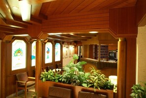 A reception area with wooden paneling, a bar, and a seating area with chairs and potted plants. - Hotel Thier (Mönichkirchen)