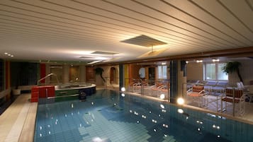 Ein Innenpool mit gefliestem Boden, Liegestühlen und einer Whirlwanne.