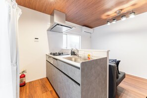 A modern kitchen with a central island, stainless steel appliances, and a wooden ceiling. - Fully Renovated / 1 Station from Ikebukuro / 6 Beds (Toshima-ku)