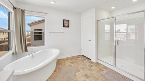 A modern bathroom with a freestanding bathtub, a glass shower enclosure, and a window with curtains. - 4000SF LUXE HOME｜Near Strip｜PoolTable｜TV in ALL Rm (Las Vegas)