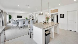 A modern kitchen with a central island, a dining area with chairs, and a living space with a sofa. - 4000SF LUXE HOME｜Near Strip｜PoolTable｜TV in ALL Rm (Las Vegas)
