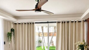 Sala de estar moderna com sofá, mesa de centro e ventilador de teto.