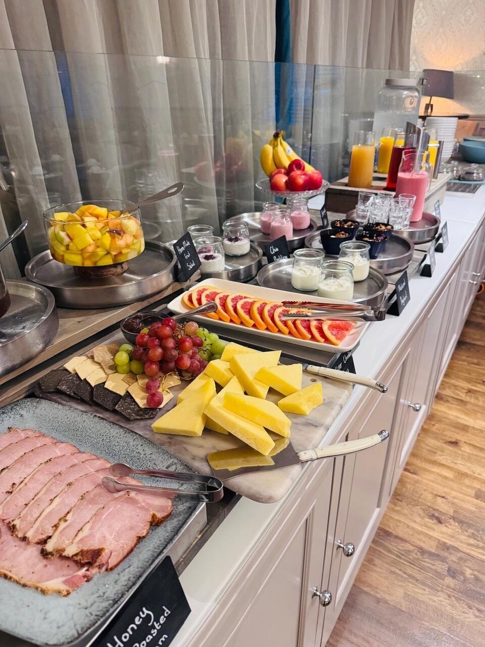 A buffet with various food items including fruits, cheeses, and meats.