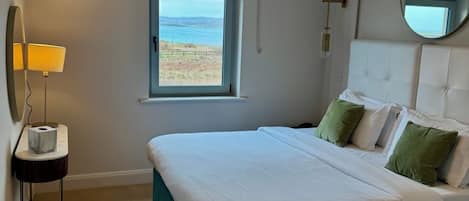 Een hotelkamer met twee bedden, een raam met uitzicht, een bedlamp en een spiegel.