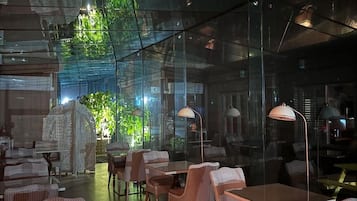 An indoor space with glass walls, wicker furniture, and a central table.