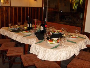 Un restaurante con mesas redondas dispuestas para comer, cada una con platos de comida, vasos y botellas de vino.