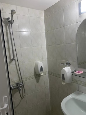 A bathroom with a shower, toilet paper dispenser, and sink. - Family Hotel Markony (Smolyan)