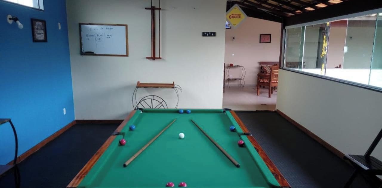 Une table de billard avec des billes, un tableau blanc avec des inscriptions et une fenêtre donnant sur un paysage.