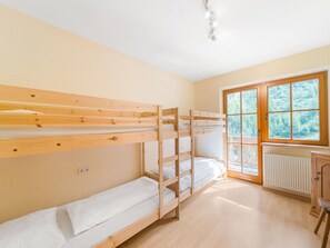A room with bunk beds, a window with a view of trees, and a radiator. - Quaint Alpine Hut In The Stubaital With Sauna (Neustift Im Stubaital)