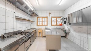 A modern kitchen with stainless steel appliances, a central island, and large windows.